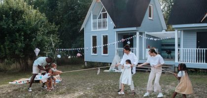 Happy family playing tug of war in front of cozy houses during a summer day.