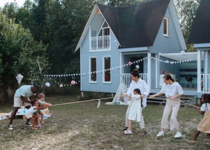 Happy family playing tug of war in front of cozy houses during a summer day.
