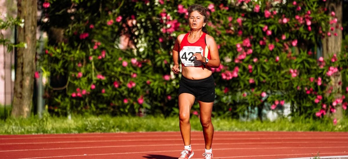 Middle aged female athlete in sportswear running during track and field competition while looking forward