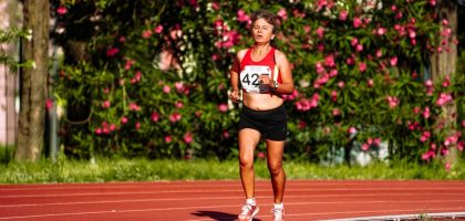 Middle aged female athlete in sportswear running during track and field competition while looking forward